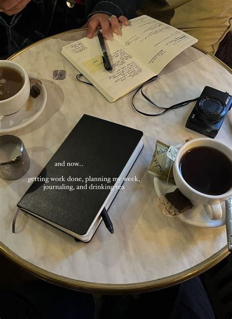 A Person Sitting At A Table With Two Cups Of Coffee And Notebooks On It