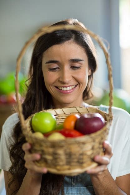 Premium Photo Smiling Woman Holding A Basket Of Fruits