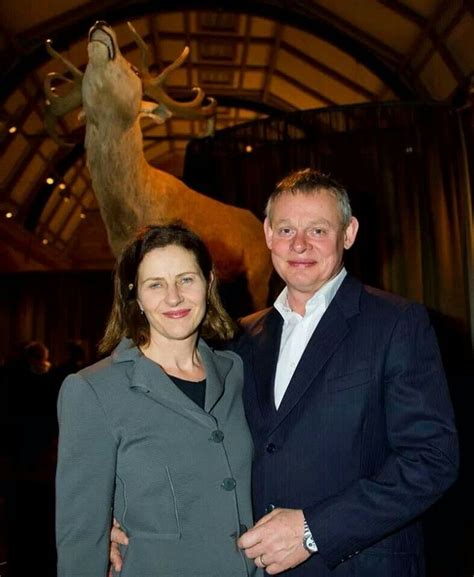 Two People Standing Next To Each Other In Front Of A Deer Statue