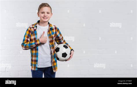 Smiling Boy Holding Soccer Hand Showing Thumb Up Sign Standing Against