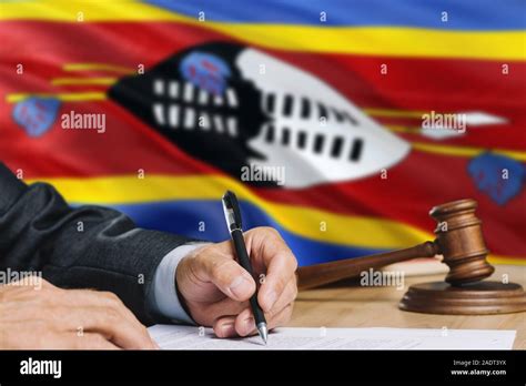 Judge Writing On Paper In Courtroom With Swaziland Flag Background