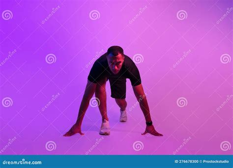 African Sportsman Posing In Crouch Start Position On Purple Background