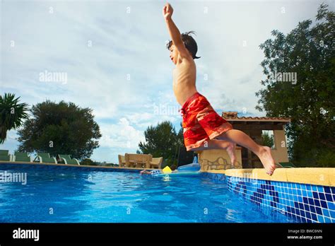 Young boy jumping into swimming pool Stock Photo - Alamy