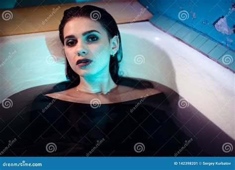 Girl With Bare Shoulders Lying In The Bathroom With Colored Purple Water Fashion Concept Stock