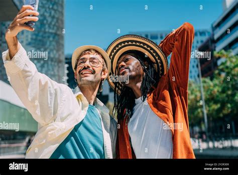 A Joyful Multiethnic Gay Couple Captures A Selfie In A Bustling City The Image Features A Black