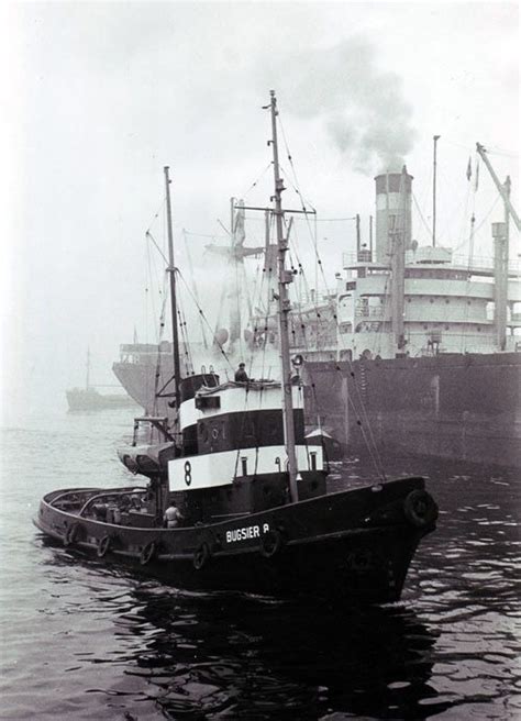 A Tug Boat In The Water Next To A Large Ship