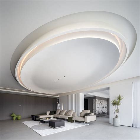 A Large Living Room With White Furniture And Circular Lighting Fixture