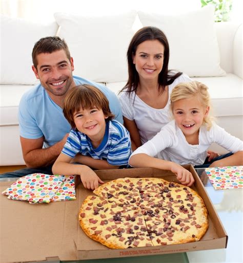 Familia comiendo pizza en el sofá Foto Premium