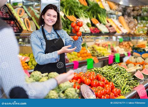 Female Shopping Assistant Helping Customer To Buy Fruit And Vegetables In Grocery Shop Stock