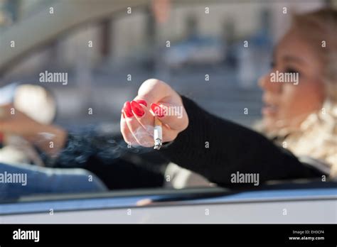 A Driving Blonde Woman Shakes Down Her Cigarettes Ash Out The Window