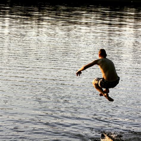 Premium Photo Rear View Of Shirtless Man Jumping Over Lake