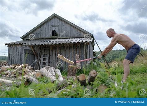 Strong Man With A Naked Torso Choping Wood With A Large Steel Ax In The