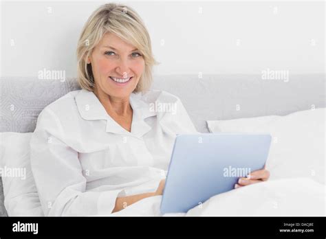 Blonde Woman Sitting In Bed Using Tablet Pc Stock Photo Alamy