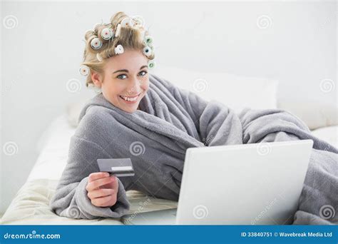 Joyful Relaxed Blonde Woman In Hair Curlers Buying Online With Her