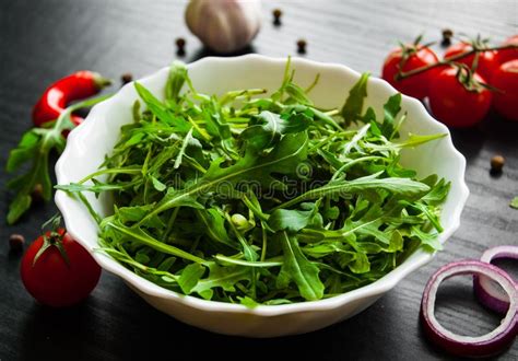 Salada Fresca De Rucola Na Bacia Branca No Fundo De Madeira Escuro Foto