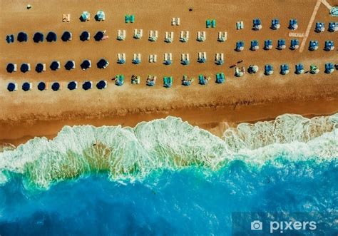 Fototapeta Piaszczysta plaża z leżakami i parasolami w równych rzędach