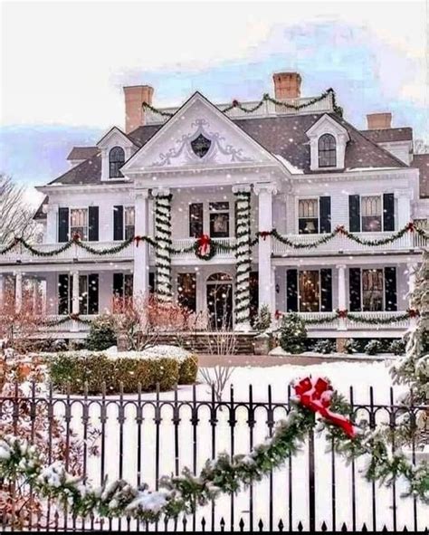 A Large White House Decorated For Christmas With Wreaths And Lights On