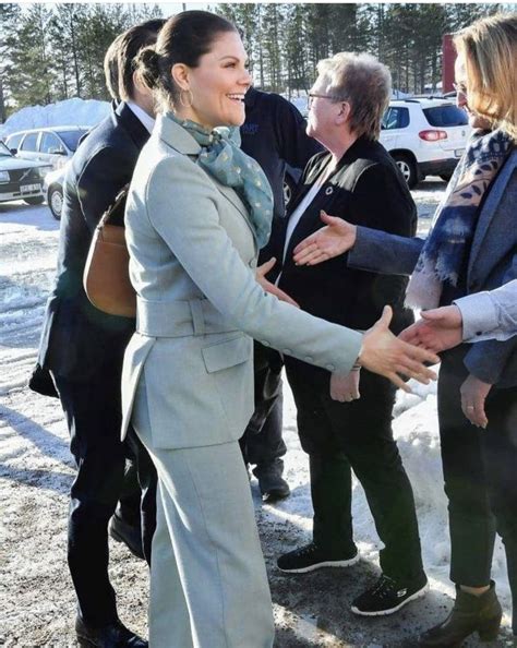 Two Women Shaking Hands In The Snow With Other People Standing Around