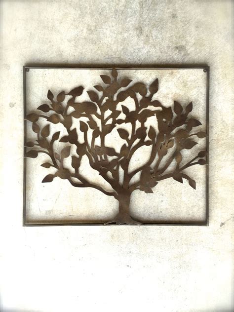 a metal tree is mounted to the side of a white wall, with leaves on it