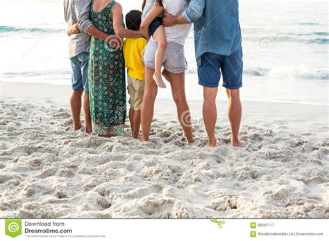 Vista Posterior De Una Familia Feliz Que Presenta En La Playa Imagen De