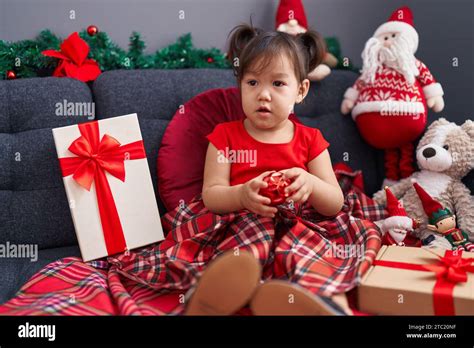 Adorable Chinese Girl Holding Ball Sitting On Sofa By Christmas