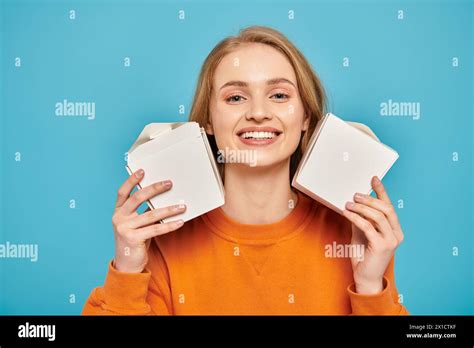 A Woman With Blonde Hair Holds Two Boxes In Front Of Her Face