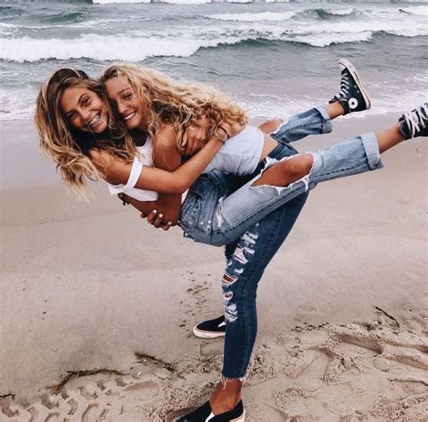 Two Women Are Hugging On The Beach While One Woman Is Holding Her Leg