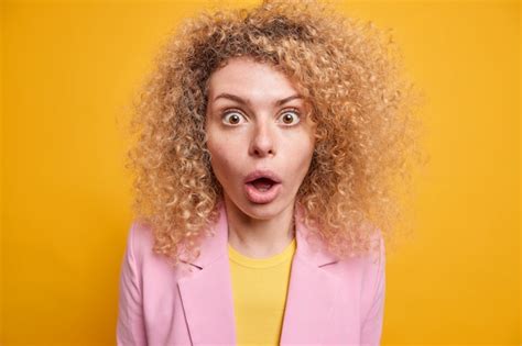 Foto De Estudio De Una Mujer Joven Sorprendida Con El Pelo Rizado Y