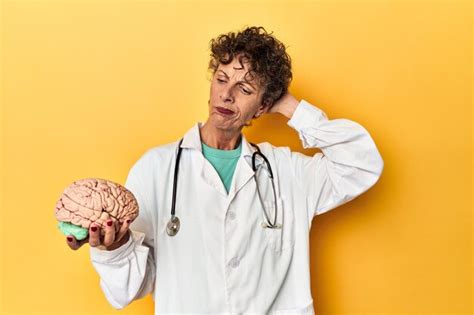 Doctor Sosteniendo Un Modelo De Cerebro En Un Estudio Amarillo Tocando