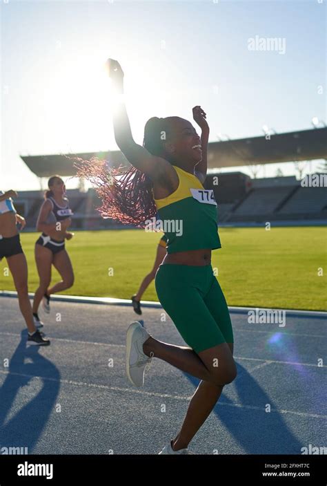 Happy Female Track And Field Athlete Winning Race On Sunny Track Stock