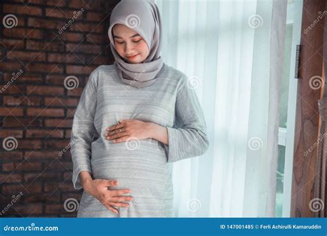 Pregnant Muslim Woman Embracing Her Belly Posing Over Grey Background