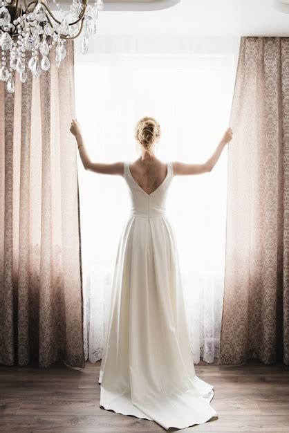 La novia y el novio están de pie contra la ventana mirando afuera