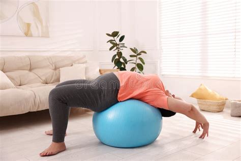 Overweight Mature Woman Doing Exercise With Fitness Ball At Home Stock