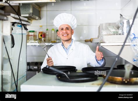 Friendly Smiling Mature Man Chef In Uniform Standing With Frying Pans