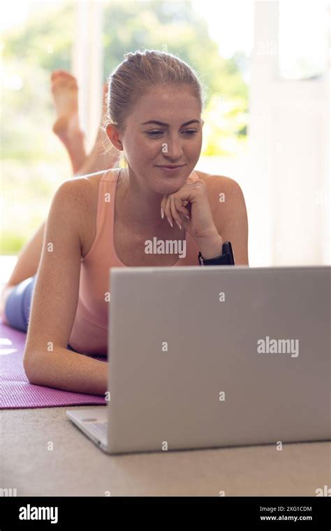 Using Laptop Woman Lying On Yoga Mat At Home Focusing On Screen Stock