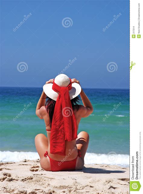 Frau Im Roten Bikini Der Auf Dem Strand Justiert Hut Sitzt Stockfoto