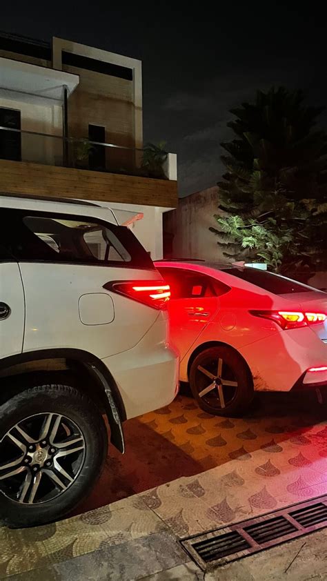 Two Cars Parked Next To Each Other In Front Of A Building With Lights