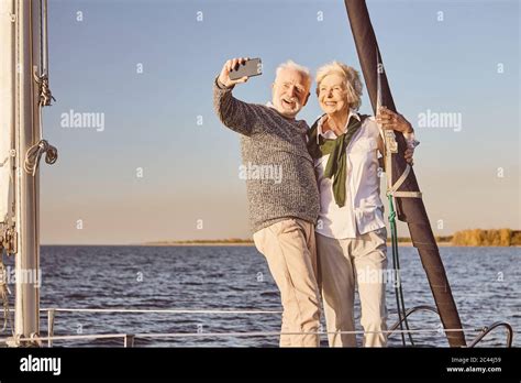 Happy Senior Couple Standing On The Side Of Sail Boat Or Yacht Deck