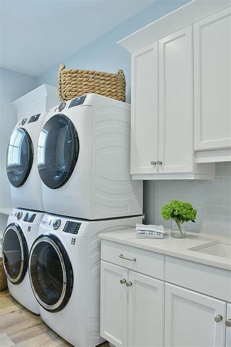 Laundry Room Features Dual Stacked Washer And Dryers And White Cabinets