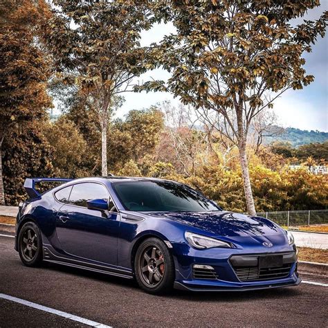 A Blue Sports Car Is Parked On The Side Of The Road In Front Of Some Trees