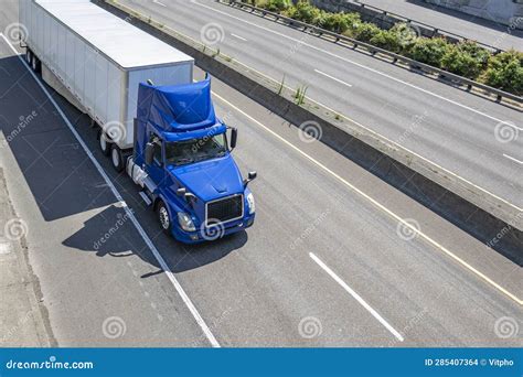 Blue Day Cab Big Rig Semi Truck With Roof Spoiler Transporting Cargo In