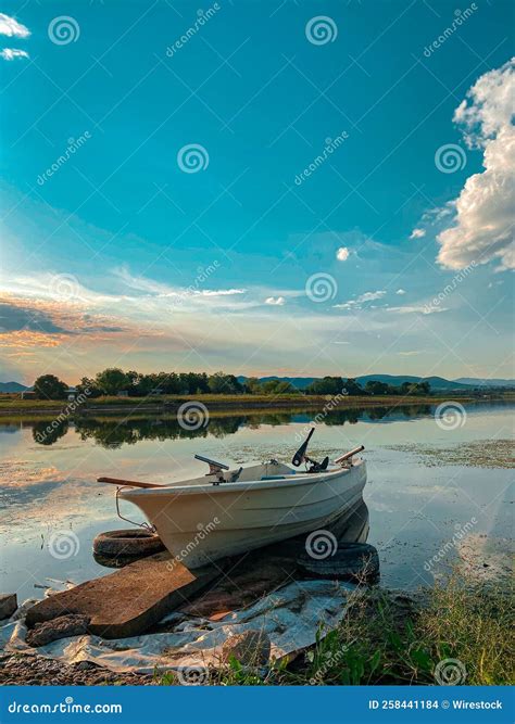 Vertical Shot Of A White Boat In A Lake Under The Cloudy Sky Stock