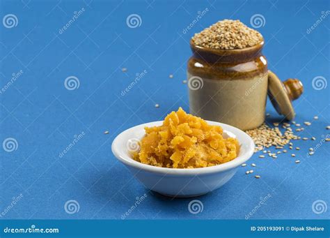 Sesame Seeds In Clay Pot With Jaggery In Bowl On Blue Background Stock