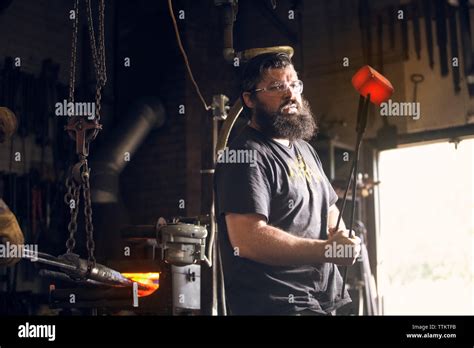 Blacksmith Holding Red Hot Metal With Tongs In Workshop Stock Photo Alamy