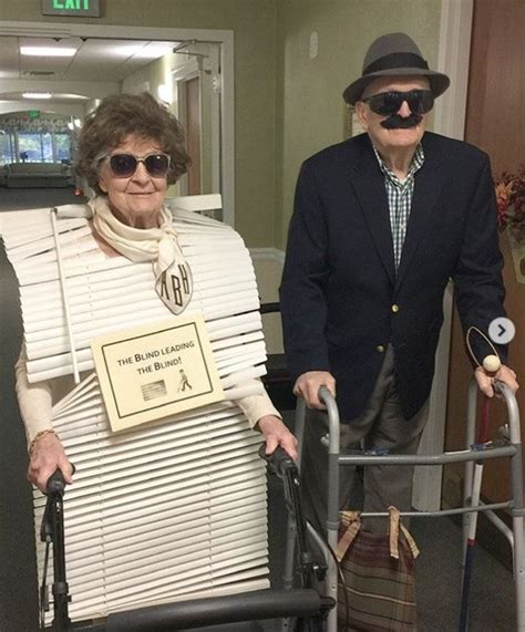 Two Elderly People With Canes And Hats In An Office Hallway One