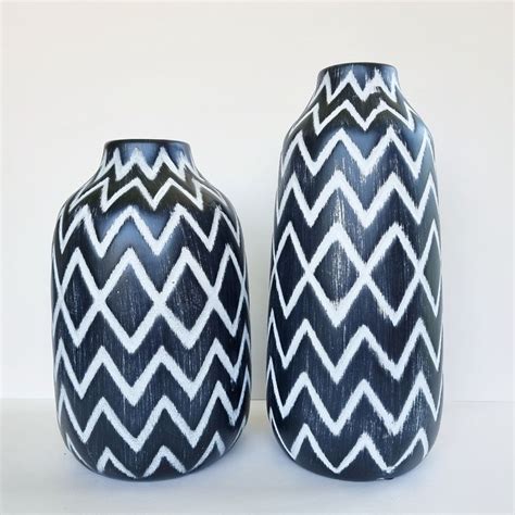 Two Black And White Vases Sitting Next To Each Other