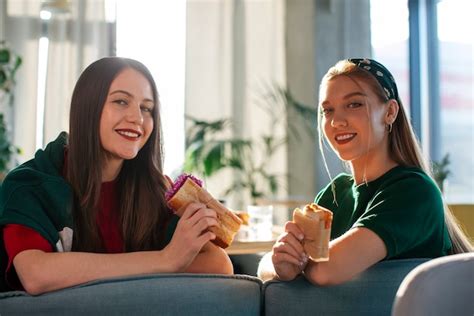 Vue Latérale Des Femmes Tenant Un Sandwich Enveloppé En Papier Photo