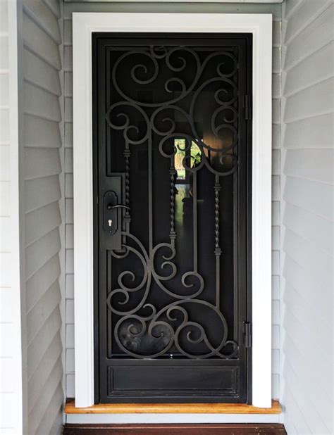 A Black Iron Door On The Side Of A House With White Trim And Wood Steps