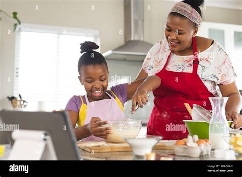 Happy African American Mother And Daughter Baking Cupcakes Mixing Ingredients In Bowl In