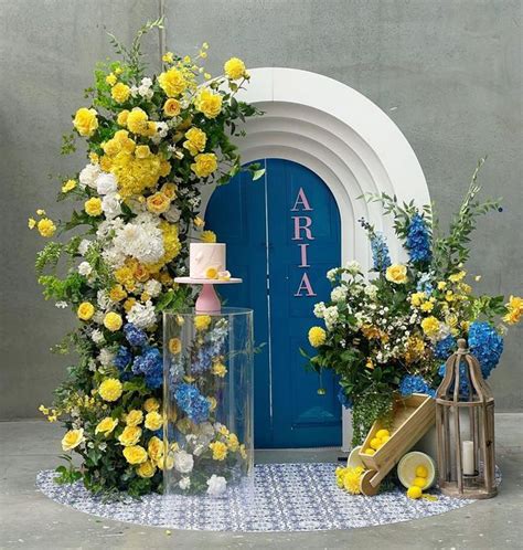 A Blue Door With Yellow And White Flowers On It Next To A Glass Case